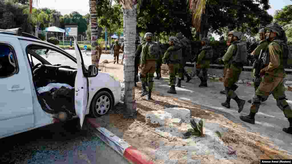 Израильские солдаты проходят мимо погибшего в в Сдероте, на юге Израиля, во время массового проникновения боевиков ХАМАС из сектора Газа на территорию Израиля  7 октября 2023 года