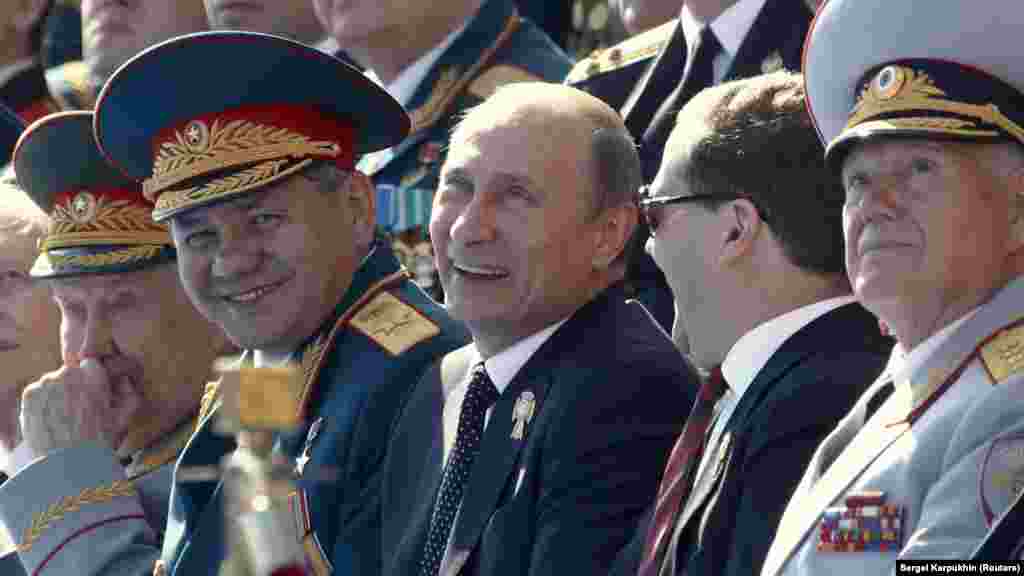 В 2013 году во время парада продемонстрировали новые военные вертолеты Ка-52 и Ми-28, новые истребители Су-34 и модернизированные самолеты Су-27 и МиГ-29. На фото слева направо: министр обороны Сергей Шойгу, президент России Владимир Путин, премьер-министр Дмитрий Медведев