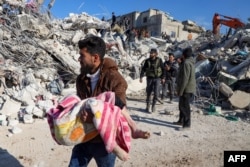 Мужчина с телом ребенка, которое достали из-под завалов дома в городе Харим. 8 февраля 2023 года. Фото: AFP