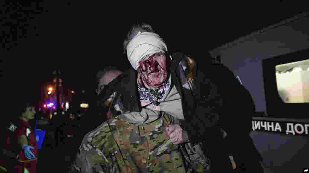 Украинский солдат несет раненую женщину из ее дома, пострадавшего в результате российской атаки на Киев