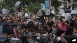 Палестинцы рядом с общественной кухней, где раздают еду. Город Газа, 14 июля 2025 года