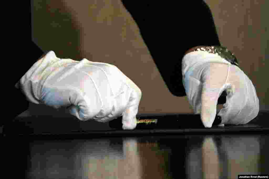 Северокорейский помощник кладет на стол ручку – ее тщательно протерли для лидера Северной Кореи перед церемонией подписания документа с президентом США