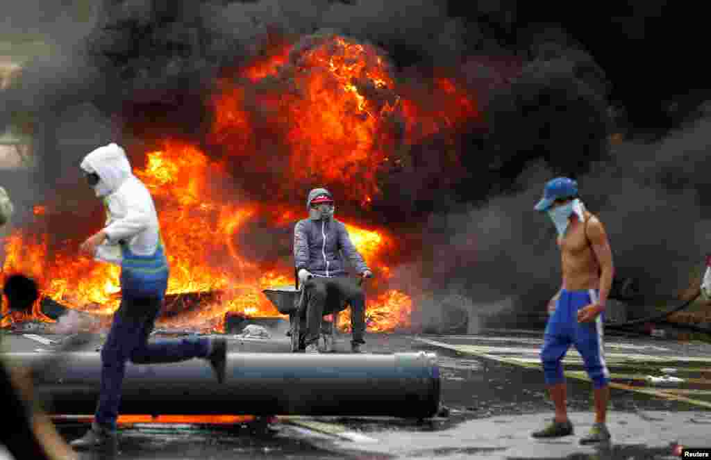 Третий год в Венесуэле продолжаются протесты населения из-за нехватки продуктов питания и медикаментов. Страна по сути находится в режиме чрезвычайного положения. Почти два миллиона людей подписали петицию за отставку президента Мадуро, а в столице уже третий год десятки тысяч венесуэльцев регулярно выходят на акции протеста. На фото – демонстранты на фоне горящих покрышек в Каракасе, столице Венесуэлы. 24 апреля 2017 года