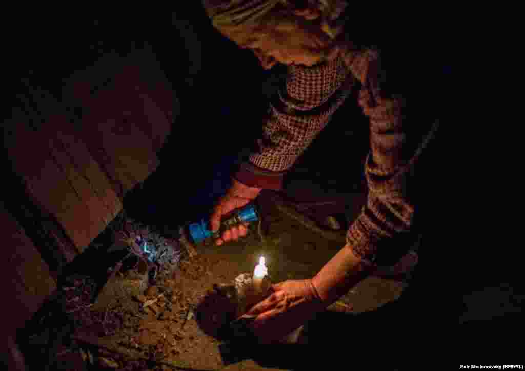 Женщина показывает неразорвавшийся снаряд, застрявший в полу ее дома. Дебальцево 