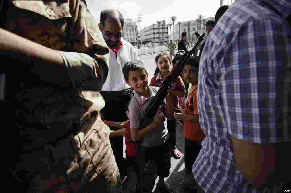 В период правления Муаммара Каддафи Ливия активно покупала оружие, в том числе бельгийское и американское огнестрельное оружие, противопехотные и противотанковые мины и тяжелую артиллерию. После свержения режима Каддафи значительная часть ручных гранатометов, противотанковых мин и установок "Град" оказалась в руках джихадистов из Мали и Алжира, которые в 2013 году вели партизанскую войну за независимость На фото – ливийский мальчик с отцовским автоматом Калашникова во время передачи оружия на Площади мучеников в Триполи после свержения Каддафи. Сентябрь 2012 года