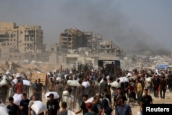 Жители Газы несут мешки с гуманитарной помощью в городе Бейт-Лахиа на севере сектора. 27 июля 2025 года