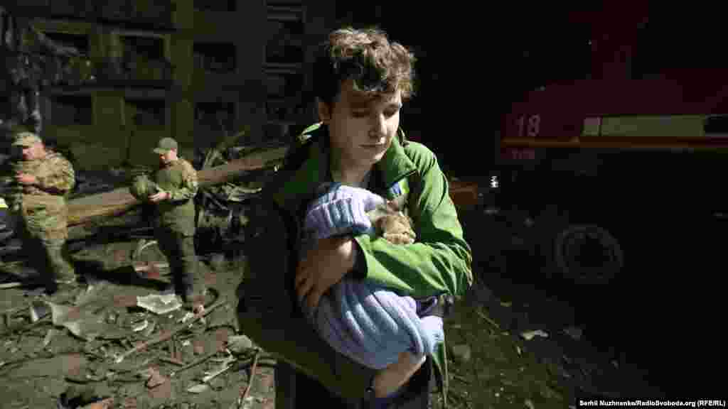 Мальчик несет на руках кота, которого вытащили из-под завалов жилого дома, пострадавшего от попадания российской ракеты в Святошинском районе Киева