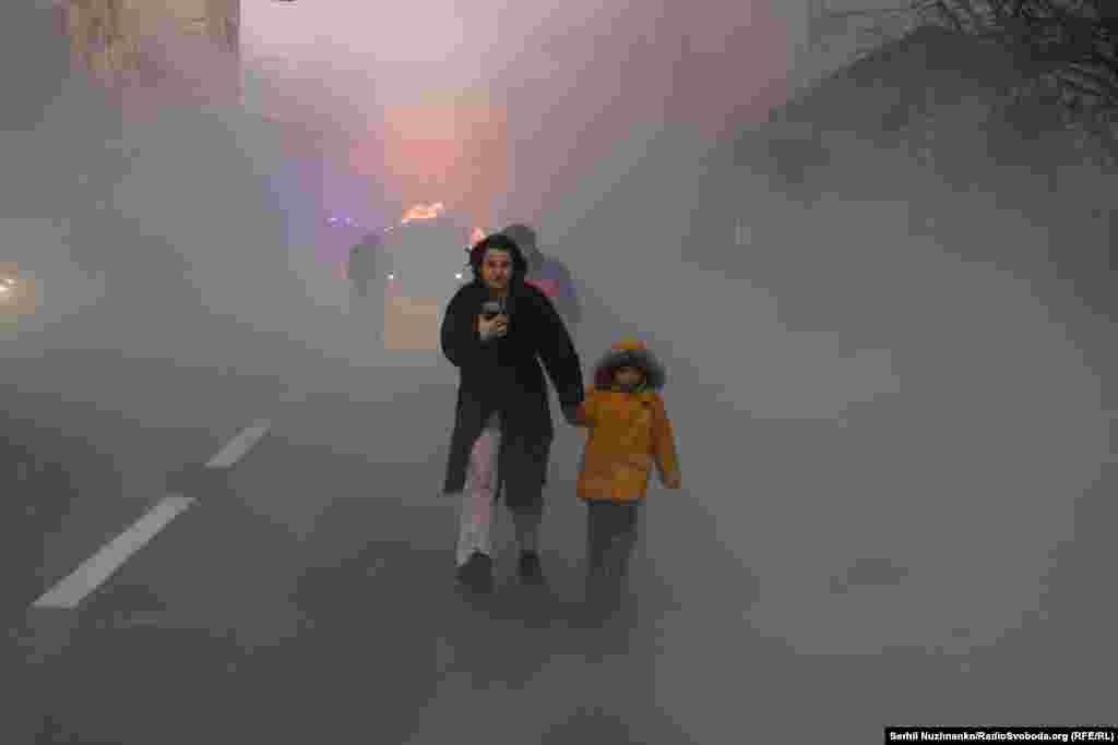 Мать уводит ребенка от места падения российского снаряда на Киев 20 декабря 2024 года. 