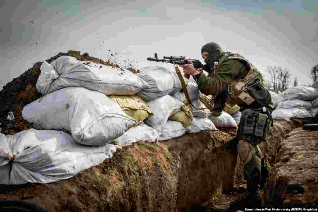 Боец украинского батальона "Азов" стреляет из автомата Калашникова. Вблизи села Широкино в Донецкой области. 18 апреля 2015