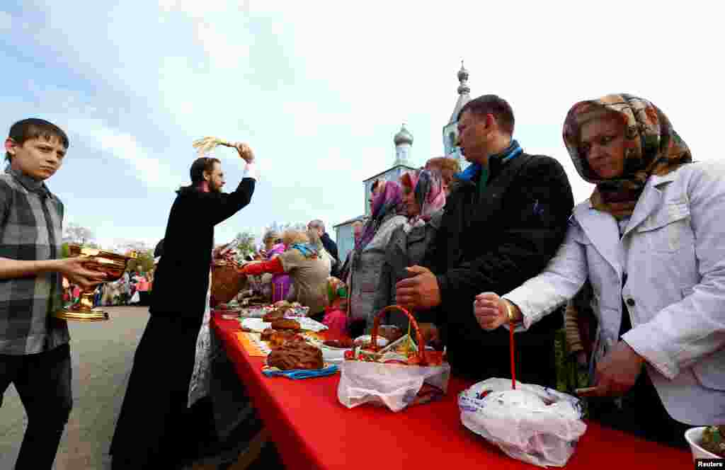 В течение Великой субботы, предшествующей Пасхе, принято освящать куличи, пасху, крашенки и другие продукты На фото – церковный служитель освящает еду прихожан. Бобруйск, Беларусь