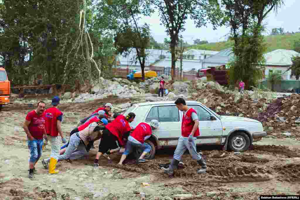 Необходимость расчистки улиц и дворов объединила неравнодушных горожан. В пострадавшем от селя поселке Карагайлы работают десятки волонтеров, в том числе и дети На фото - добровольцы общественного фонда "Шугыла" помогают вытаскивать застрявший в грязи автомобиль